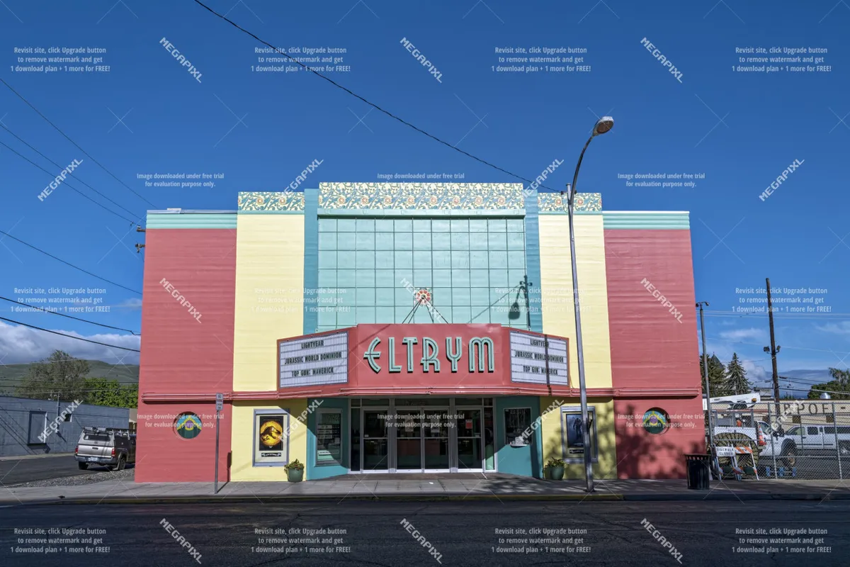 A brightly lit historic theater marquee with a colorful facade, entrance doors, and ornate roof details. The setting is lively, evoking memories of community events and entertainment in a small town.