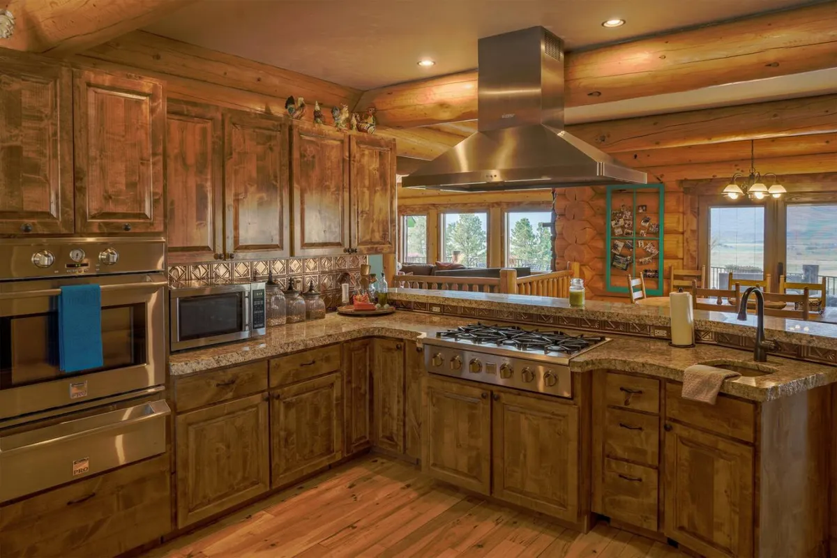 A gourmet kitchen with a large island for food prep, stainless steel appliances, rich wooden cabinetry, and ample window views. The space is clearly designed for hosting and entertaining, with room for multiple people to gather, cook, and converse.