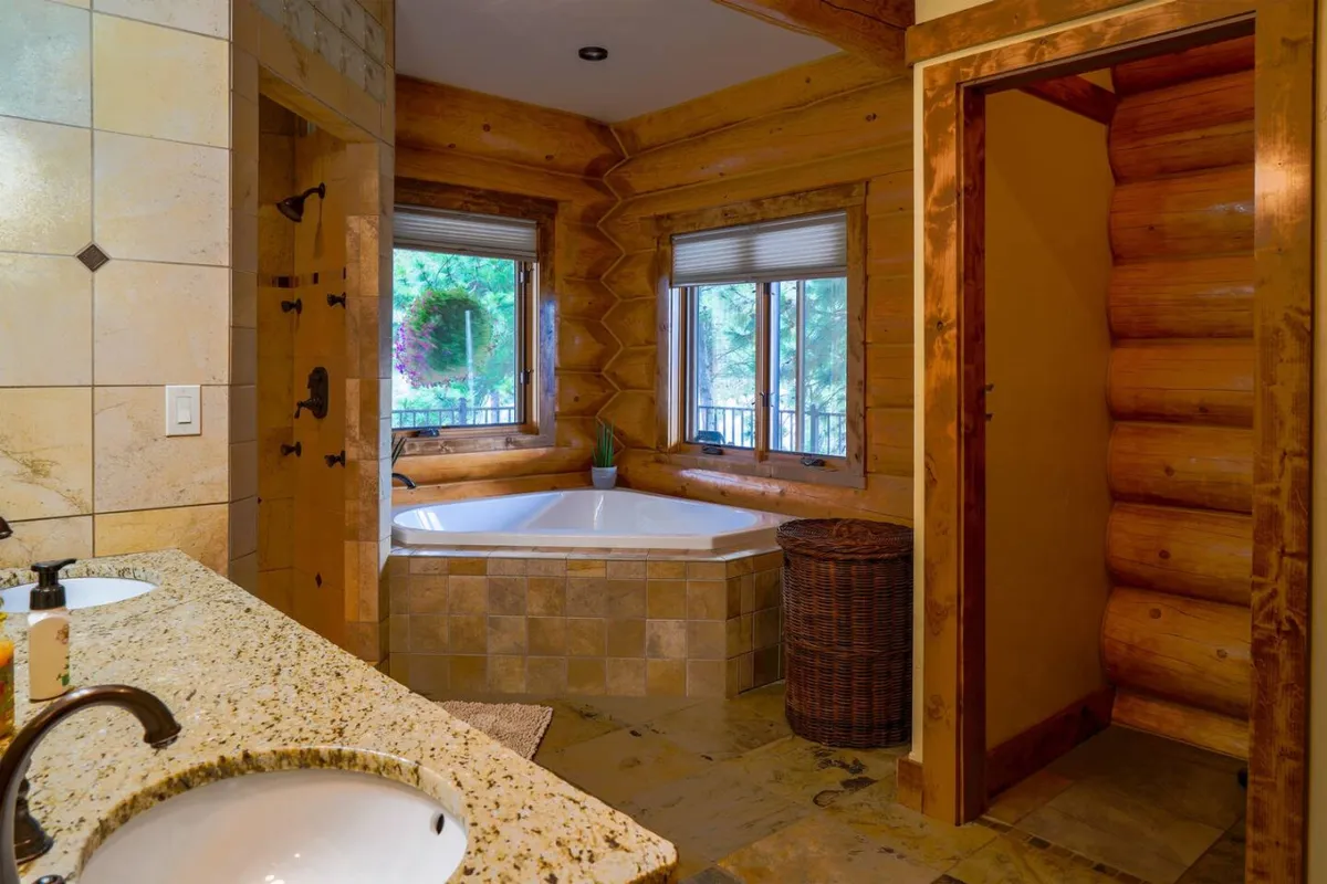 A serene bathroom with a spacious bathtub, double sink vanity, wood accents, and windows that invite natural light. The setting exudes spa-like luxury and relaxation, perfect for unwinding after a day outdoors.