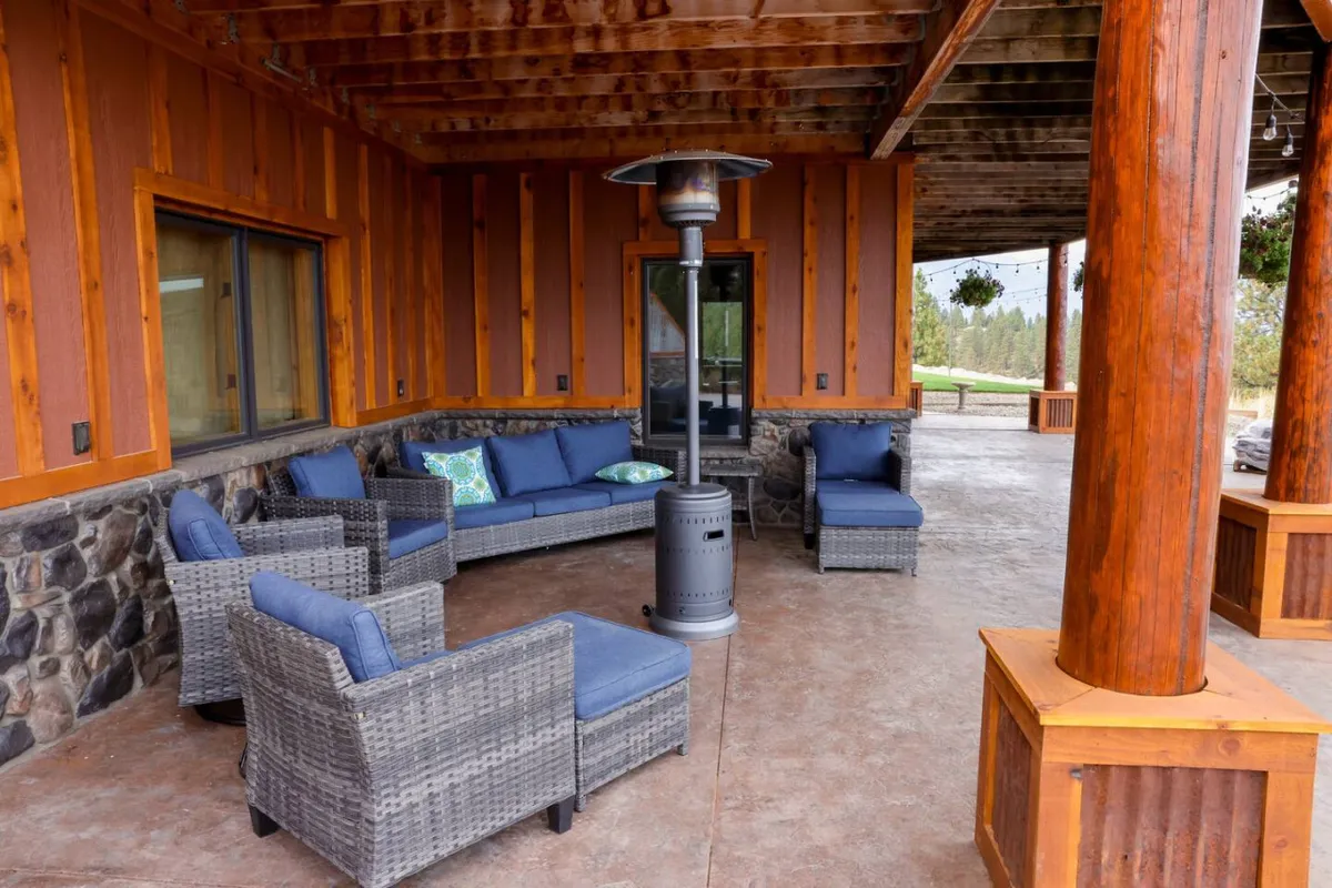 A cozy outdoor seating area is arranged around a patio heater, sheltered by sturdy wooden pillars. The space invites intimate conversations and relaxation while taking in sunset views or enjoying the evening air. The design blends rustic charm with comfort, echoing the lodge's tranquil and welcoming environment.