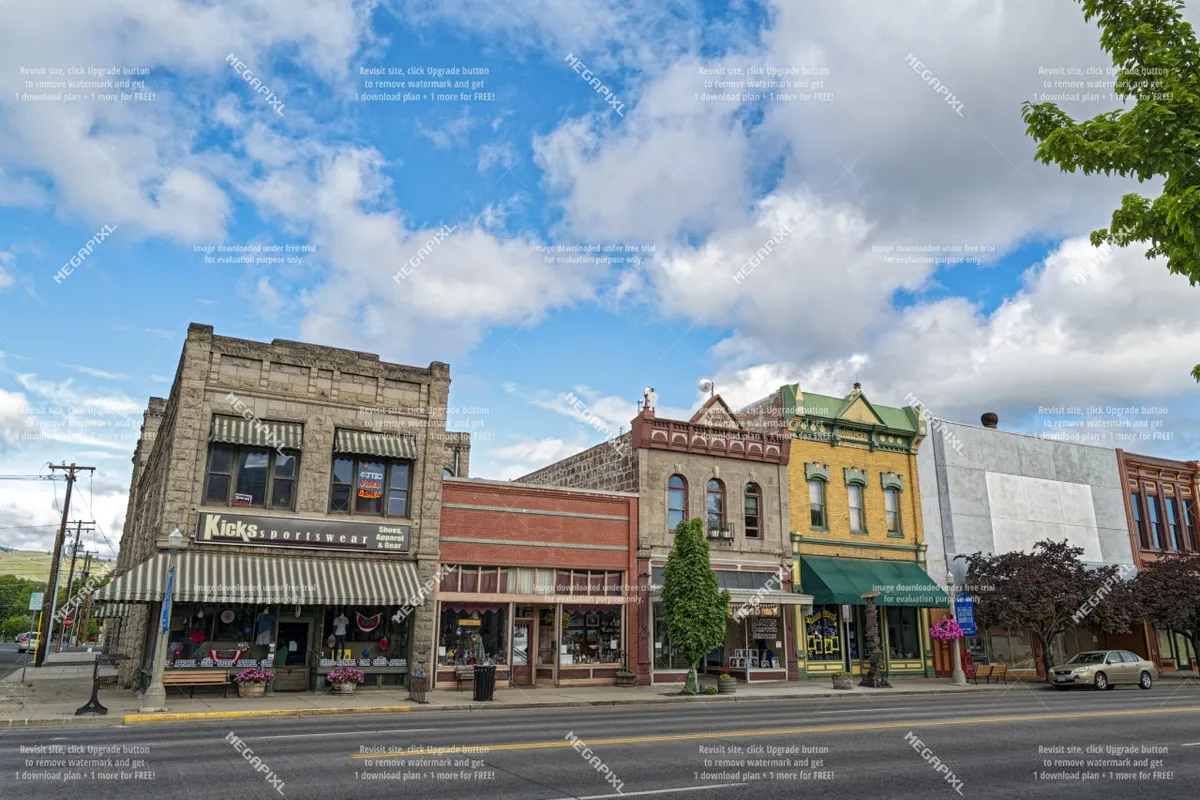 A vibrant street scene in Baker City, with beautifully preserved historic buildings, colorful storefronts, and tree-lined sidewalks. People are seen strolling, window shopping, and enjoying the lively atmosphere.