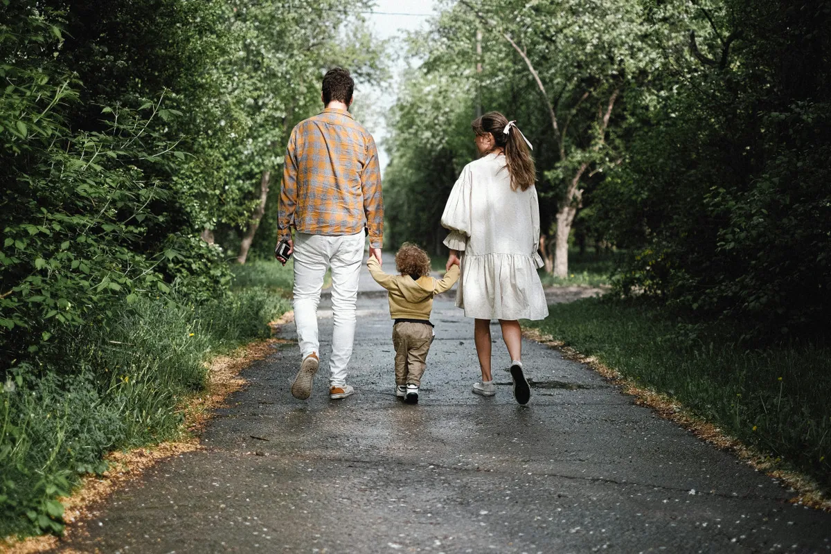 A happy family walks along a pathway surrounded by lush greenery, sharing laughter and exploring the natural setting. The scene captures the spirit of outdoor adventure and family bonding, with the vibrant foliage reflecting the region’s abundance of nature.